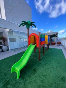 a playground with a green slide on a lawn at Vila do Centro Apart Hotel in Bombinhas