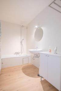 een witte badkamer met een wastafel en een spiegel bij Between Waves in Oostende