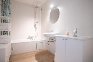a white bathroom with a sink and a mirror at Between Waves in Ostend