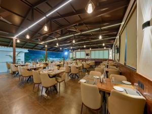 a restaurant with tables and chairs in a room at Golden Leaf Resort in Dhule