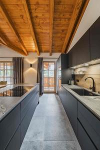 a kitchen with black cabinets and a wooden ceiling at Dachstein West Apartment T4 in Russbach am Pass Gschütt