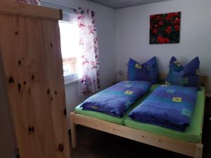 a bedroom with a bed with blue and green pillows at Feriendorf "Am Forsthaus" Mosbach in Mosbach