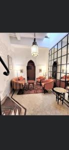 Cette grande chambre comprend des canapés et des tables. dans l'établissement Riad au cœur de la médina loué entièrement avec ménage et petit déjeuner compris, à Marrakech