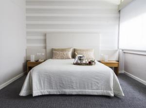 a bedroom with a large white bed with two tables at Hotel Eurosol Leiria & Jardim in Leiria