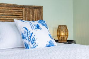 a bed with a blue and white pillow and a lamp at Fragata Island House in Cartagena de Indias