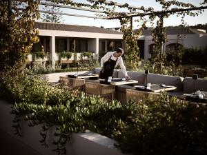 a man in an apron preparing food in a garden at Contessina Hotel in Tsilivi