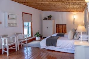 um quarto com uma cama, uma mesa e cadeiras em Killassy House em Graaff-Reinet