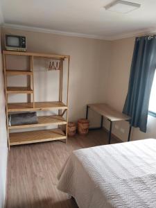 a bedroom with a bed and a table and a shelf at Apartamento Conforto in Curitiba