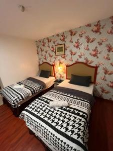 two beds in a room with floral wallpaper at MR Hotel Nusa Bestari in Skudai
