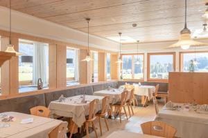 a restaurant with white tables and chairs and windows at Hotel Tyrol in Valle Di Casies