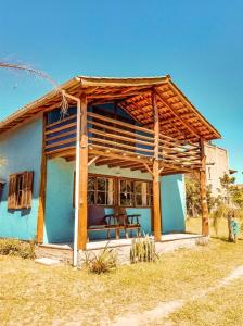 a small blue house with a wooden roof at Rosatrip Surf Bungalows in Praia do Rosa