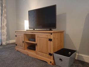 a flat screen tv on a wooden entertainment center at Maria`s Garden House in Ollerton