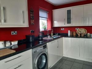 a kitchen with white cabinets and a washing machine at Maria`s Garden House in Ollerton