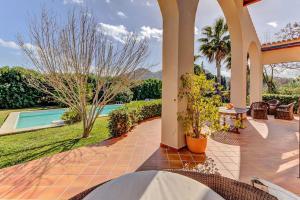 een huis met een patio en een zwembad bij Lovely Alcudia Villa Casa De Arcos Private Pool Gardens Close to Resort Centre and Beaches in Alcudia