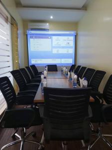 una sala de conferencias con una gran pantalla de proyección y una mesa con sillas en Joshesther Olive Hotel, en Ikeja