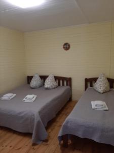 a room with two beds with towels and a clock on the wall at Гостьовий дім на Герцена Guest hous on Gertsena in Novhorod-Siversʼkyy