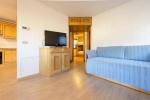 sala de estar con sofá azul y TV en Cesa te Val en Vigo di Fassa