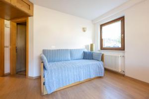 a blue couch in a room with a window at Cesa te Val in Vigo di Fassa