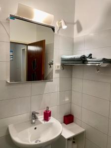 a white bathroom with a sink and a mirror at Grazer Spatz in Graz +12 photos