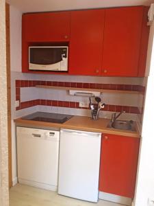 a small kitchen with red cabinets and a sink at Apartment Near The Slopes La Plagne in La Plagne