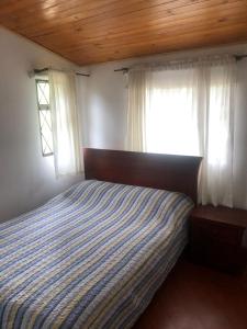 1 dormitorio con 1 cama y 2 ventanas en Hacienda Moncora cabaña lago p2, en El Rosal
