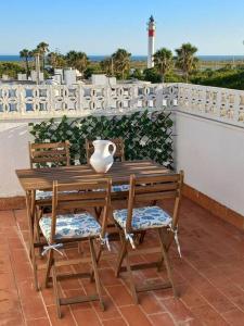 a wooden table and chairs with a vase on a balcony at Dúplex con espectaculares vistas del Rompido in El Rompido