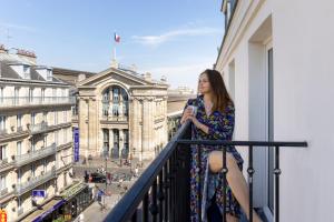 a woman standing in front of a building with a balcony at Hotel Whistler in Paris
