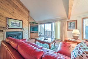 a living room with a red leather couch and a fireplace at Bellaire Resort Condo Ski, Tube, Explore! in Bellaire