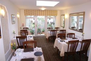 a restaurant with tables and chairs with white tablecloths at Cedar Lodge in Llandudno