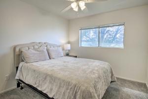 Un dormitorio con una cama con ventilador de techo y una ventana. en Comfy Bakersfield Townhome - Fire Pit and Patio, en Bakersfield