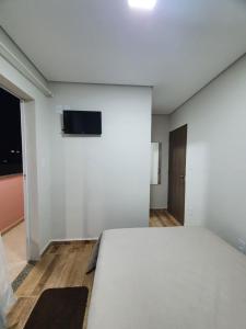 a bedroom with a bed and a tv on a wall at Suítes Nativa STL in São Thomé das Letras