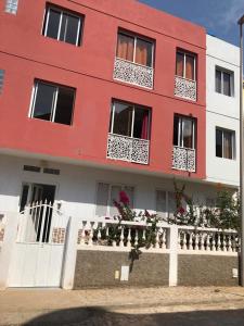 a red building with potted plants in front of it at Apart Laginha in Mindelo