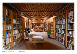 a library with shelves filled with books and a couch at Fattoria Casamora - Villa Le Magnolie in Pian di Scò
