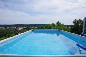 - une grande piscine avec 2 chaises bleues dans l'établissement Apartments Opsenica Barbat, à Barbat na Rabu