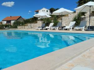 una piscina con sillas y sombrillas en Villa Sanja, Splitska, en Splitska