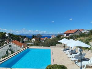 - une piscine avec des chaises longues et des parasols dans l'établissement Villa Sanja, Splitska, à Splitska