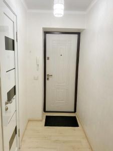 einen Flur mit einer weißen Tür und einem schwarzen Teppich in der Unterkunft Apartment on Maylin 30 12 in Turksib