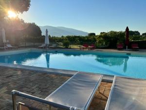 a large swimming pool with two chairs in a resort at Agriturismo Podere La Fornace in Assisi