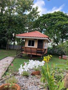 a small house with a red roof in a garden at Nantawanhomestay in Lampang