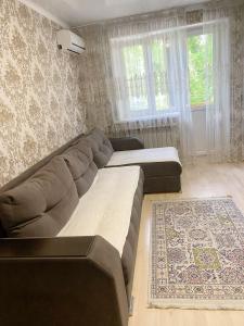 ein Wohnzimmer mit einem großen Sofa und einem Teppich in der Unterkunft Apartment on Maylin 30 12 in Turksib