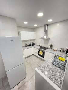 a kitchen with white cabinets and a white refrigerator at Nuevo Balmes Habitaciones in Barcelona