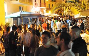 uma multidão de pessoas andando por uma rua à noite em Casa Mary em Castellammare del Golfo