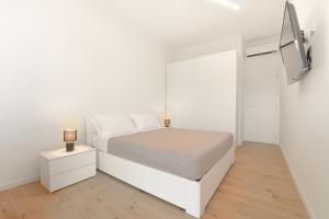 ein weißes Schlafzimmer mit einem weißen Bett und einem TV in der Unterkunft Milleventi Apartments Bologna in Bologna