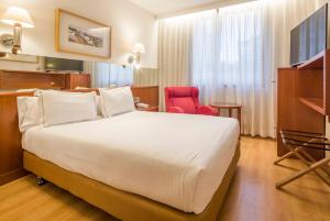 a hotel room with a large bed and a red chair at Ilunion Les Corts Spa in Barcelona