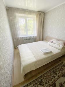 ein weißes Schlafzimmer mit einem Bett und einem Fenster in der Unterkunft Apartment on Maylin 30 12 in Turksib