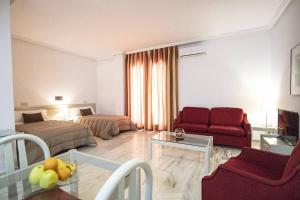 a living room with a room with two beds and a couch at Hospedium Hotel Apartamentos Simón Verde in Mairena del Aljarafe