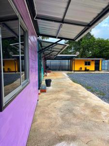 a pink building with a large window and a patio at Padang Besar Rainbow Cabin Homestay in Padang Besar