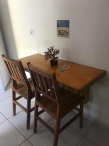 a wooden table with two chairs and a plant on it at Chalés Azuleto - Ilhabela in Ilhabela