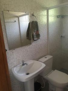 uma casa de banho com um lavatório, um WC e um espelho. em Chalés Azuleto - Ilhabela em Ilhabela