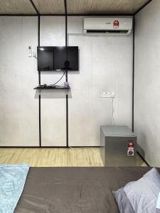 een slaapkamer met een bed en een tv aan de muur bij Padang Besar Rainbow Cabin Homestay in Padang Besar